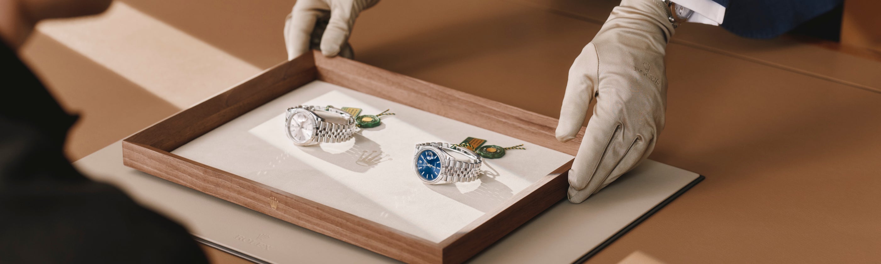 Rolex watch being shown to a woman by a man wearing a cloth glove to protect the appearance of the Rolex timepiece