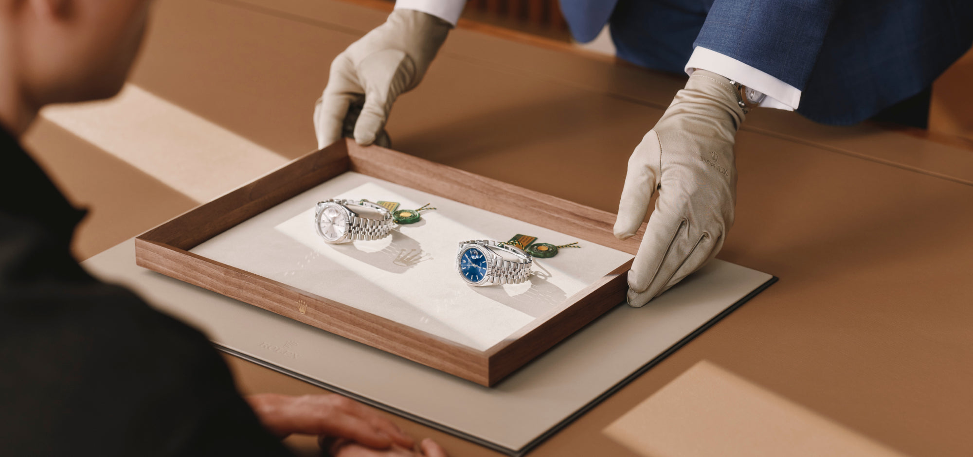 Rolex watch being shown to a woman by a man wearing a cloth glove to protect the appearance of the Rolex timepiece